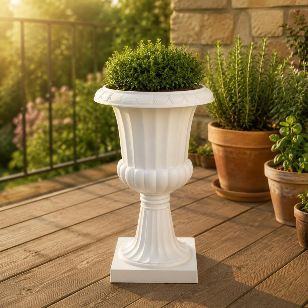 Maceta blanca acanalada con pedestal alto y una planta verde.