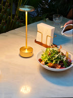 Lámpara dorada encendida junto a una ensalada.