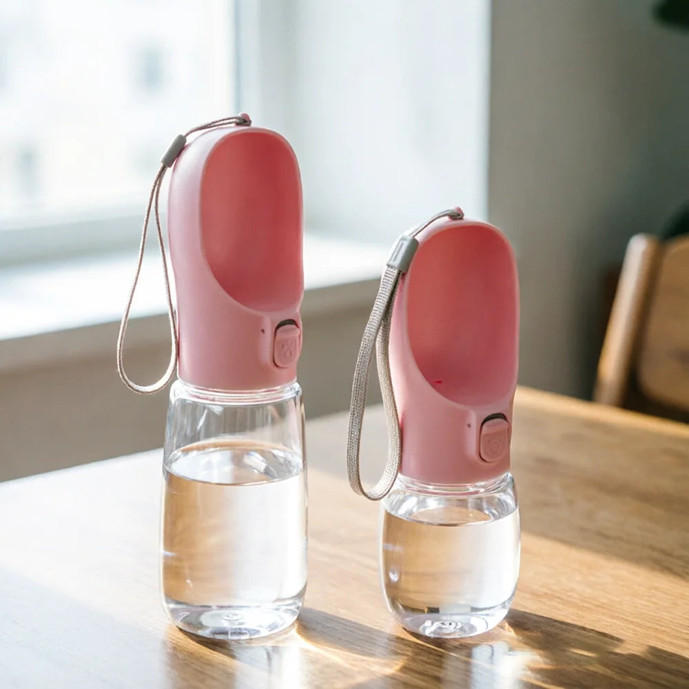 Dos botellas bebederas rosas para mascotas, de distinto tamaño y con correa.