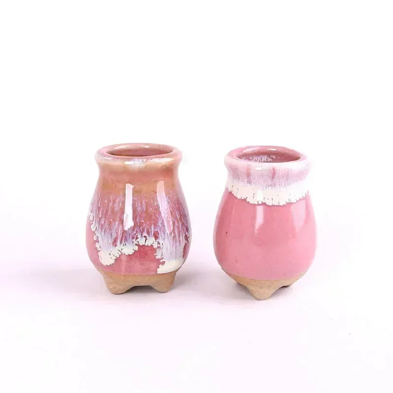 Dos macetas altas de cerámica en tonos rosa y cobrizo.