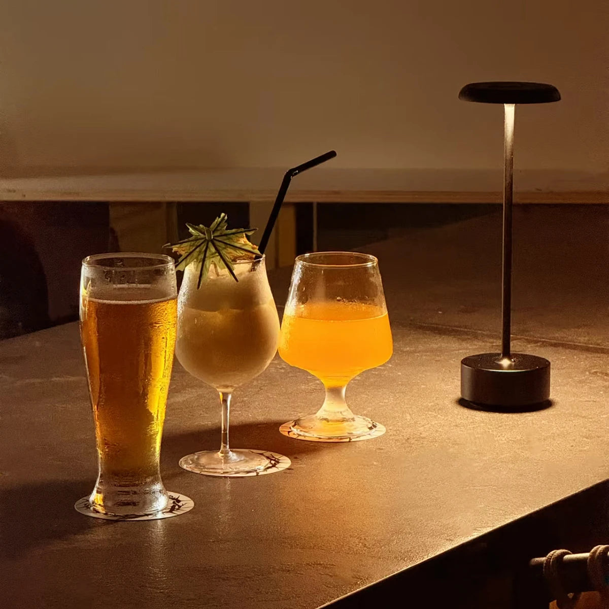 Lámpara negra junto a dos bebidas, iluminando una mesa.