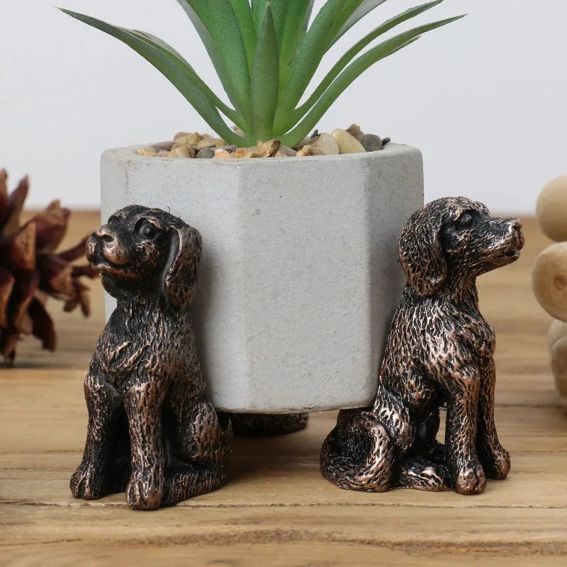 Dos soportes con forma de perro junto a una maceta gris.