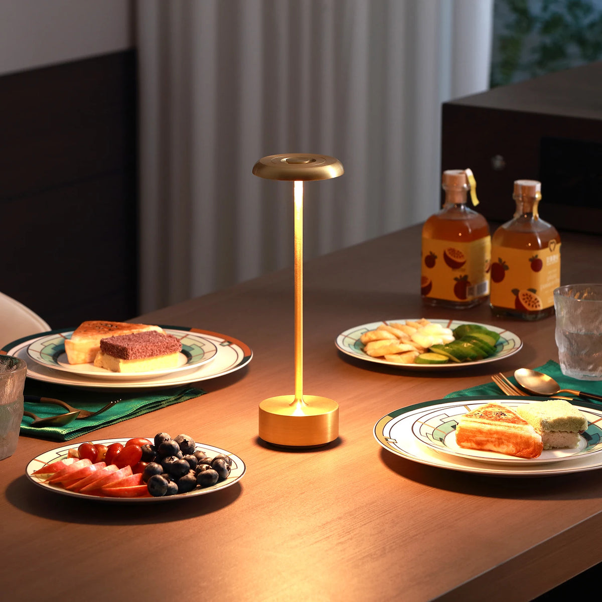 Lámpara de mesa dorada encendida sobre una mesa servida.