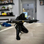 Figura negra de ninja sujetando una pluma, vista frontal sobre escritorio