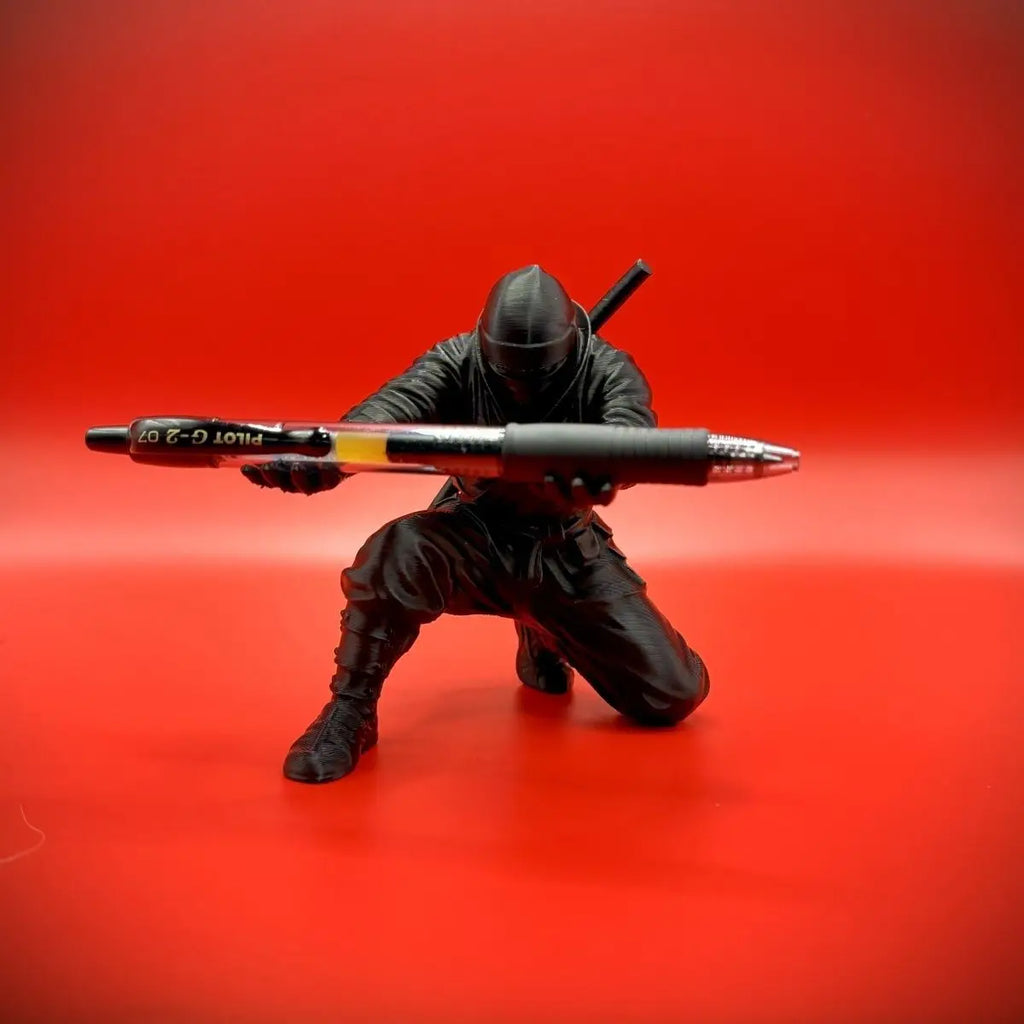 Portapluma negro de ninja con una pluma sobre fondo rojo