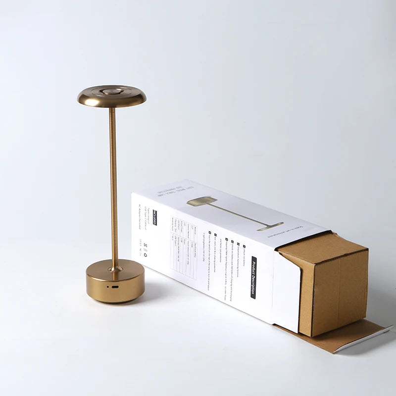 Lámpara de mesa dorada con su caja.