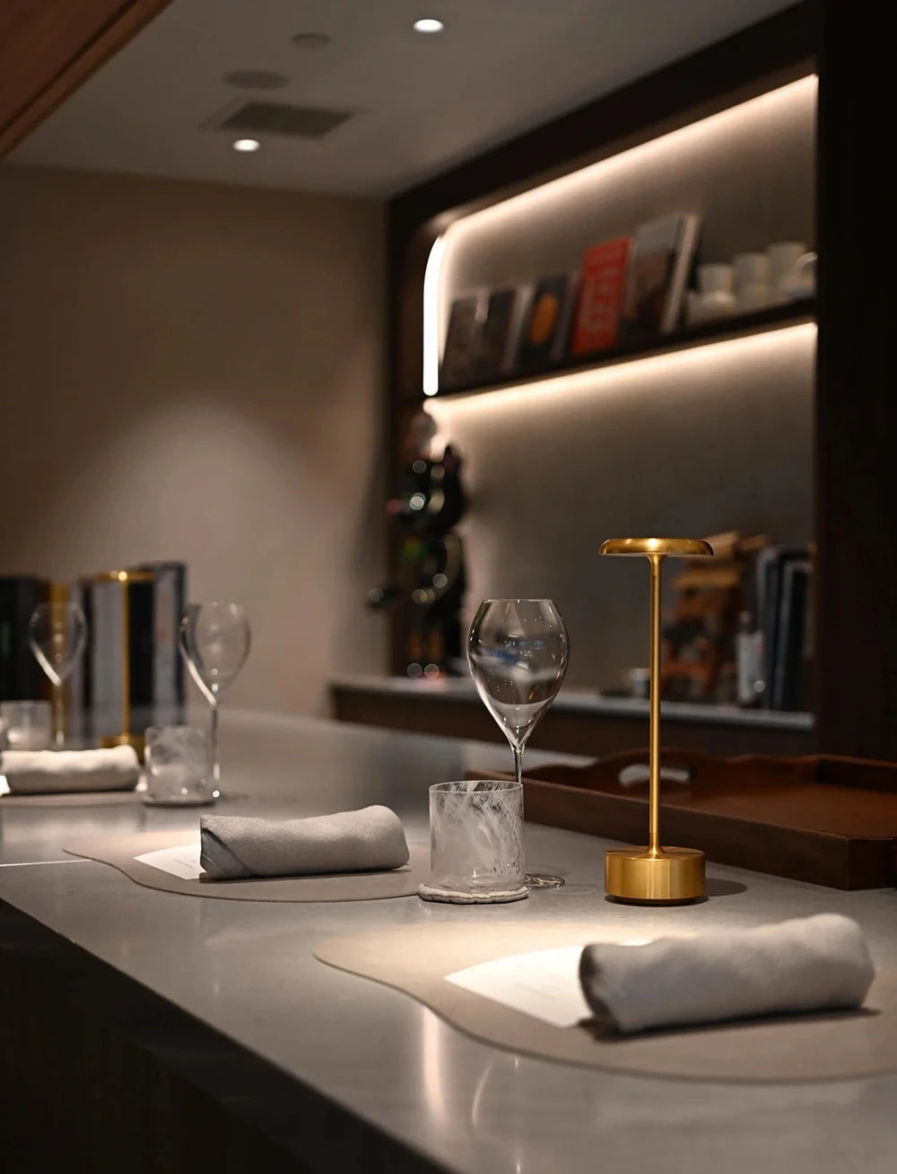 Lámpara de mesa dorada iluminando una mesa de restaurante.