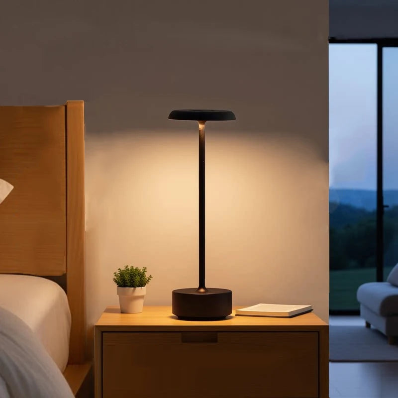Lámpara negra encendida sobre una mesa de noche.