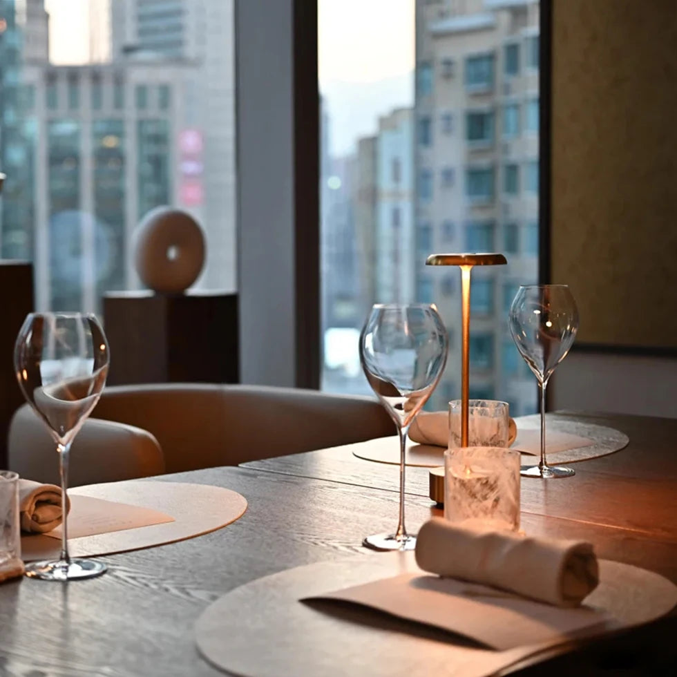 Lámpara de mesa dorada junto a una ventana de restaurante.