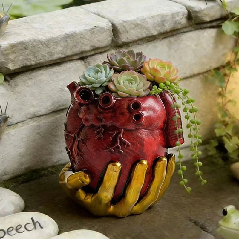 Maceta de corazón anatómico con suculentas junto a un muro de piedra.