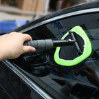 Cepillo con funda verde limpiando el vidrio exterior de un automóvil