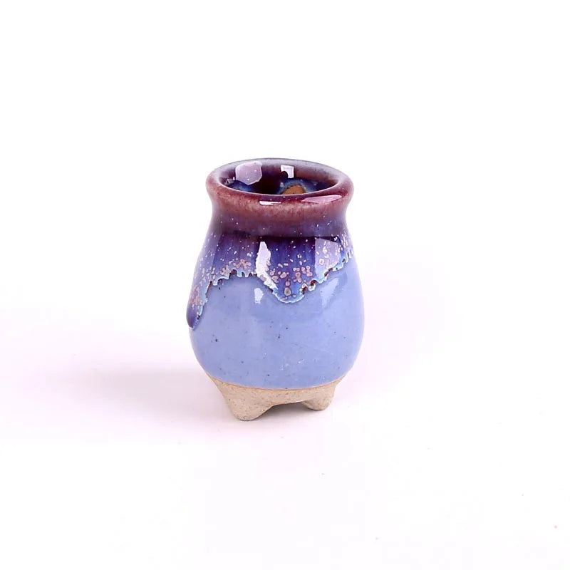 Maceta alta de cerámica azul y violeta con pequeñas patas.
